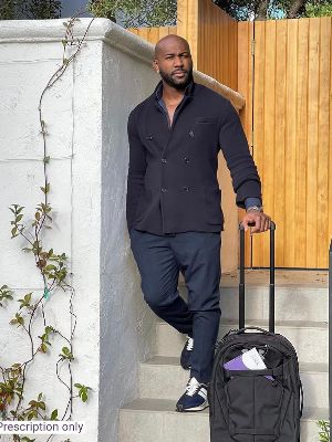 Dolvett Quince posing for a full-figure picture in a black suit.